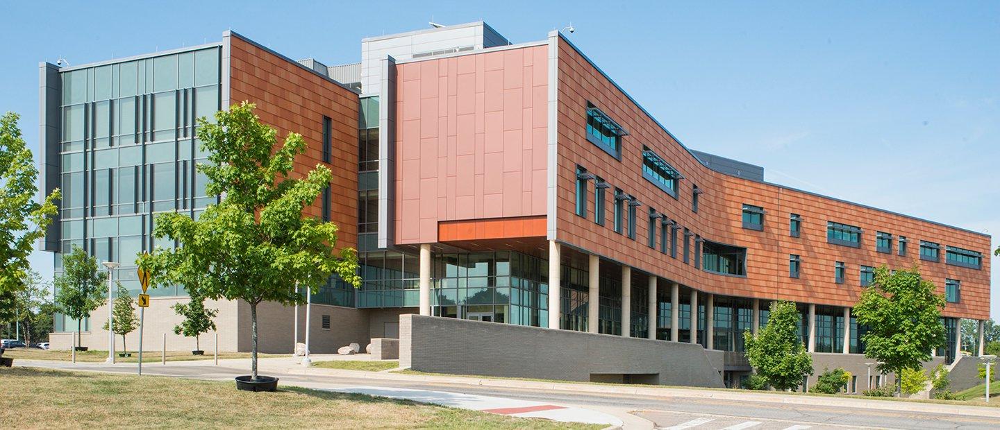 exterior of a brick and glass building with green trees around it